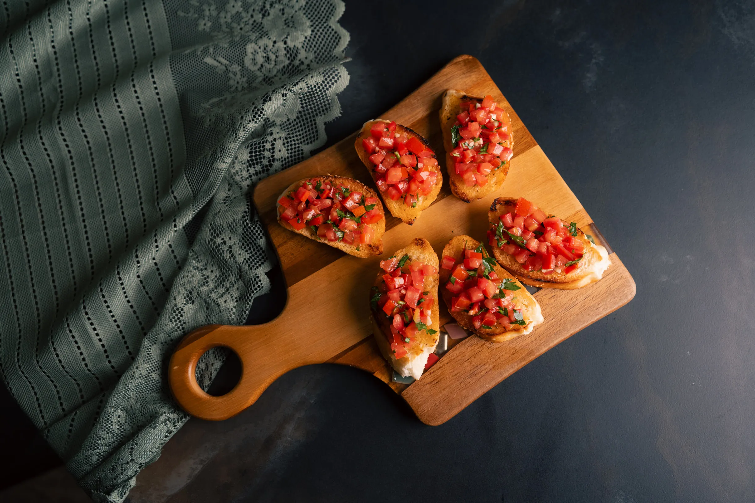 Tomato and basil bruschetta on a wooden serving board, seen from above