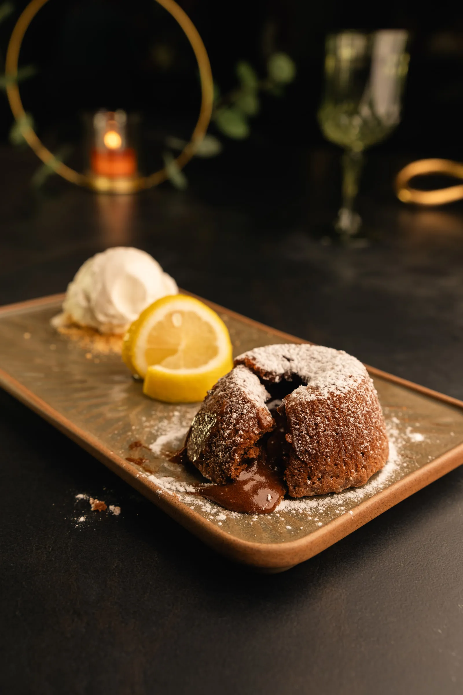 Molten chocolate cake dusted with icing sugar, with a scoop of vanilla ice cream and lemon