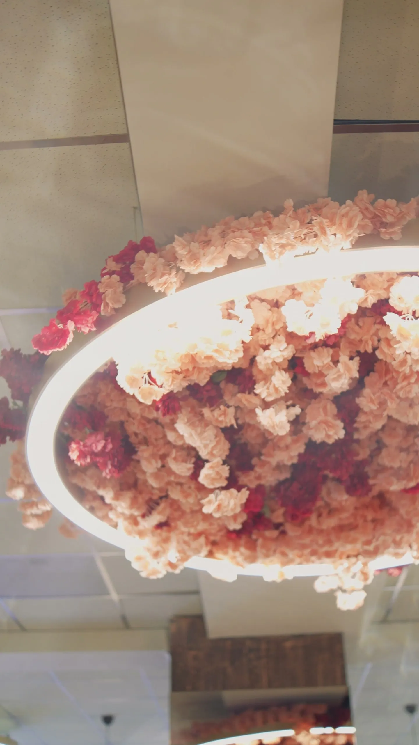 Looking up at the ring chandelier covered in pink and red flowers