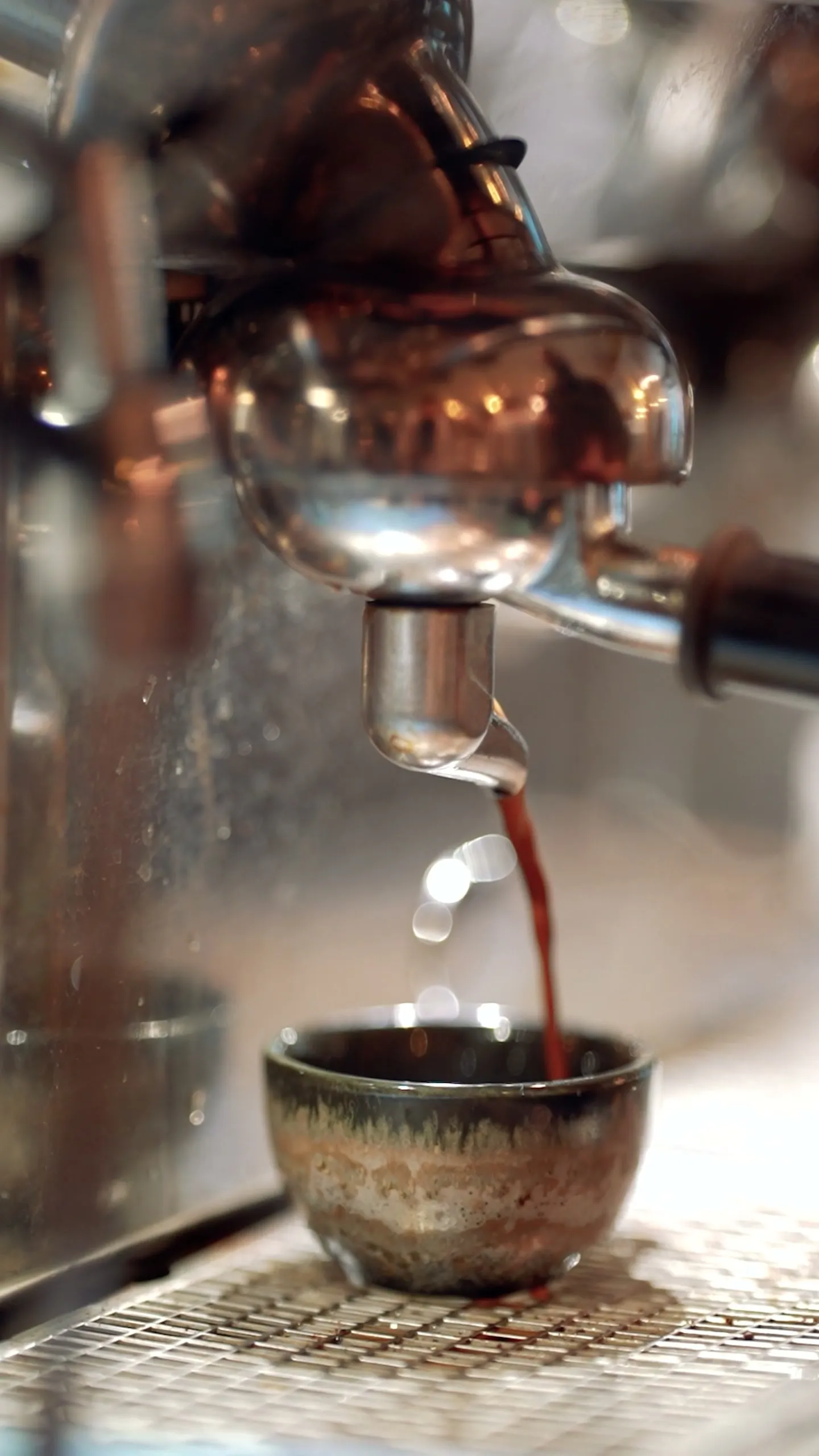 Espresso pouring from the machine into a glazed ceramic cup