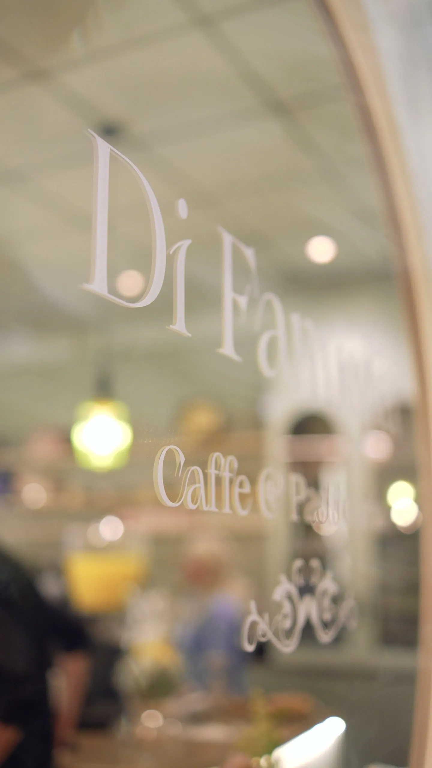 Di Famiglia lettering etched on the arched window glass, the café softly out of focus behind